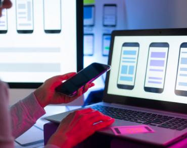 mobile phone in hand and second hand on laptop